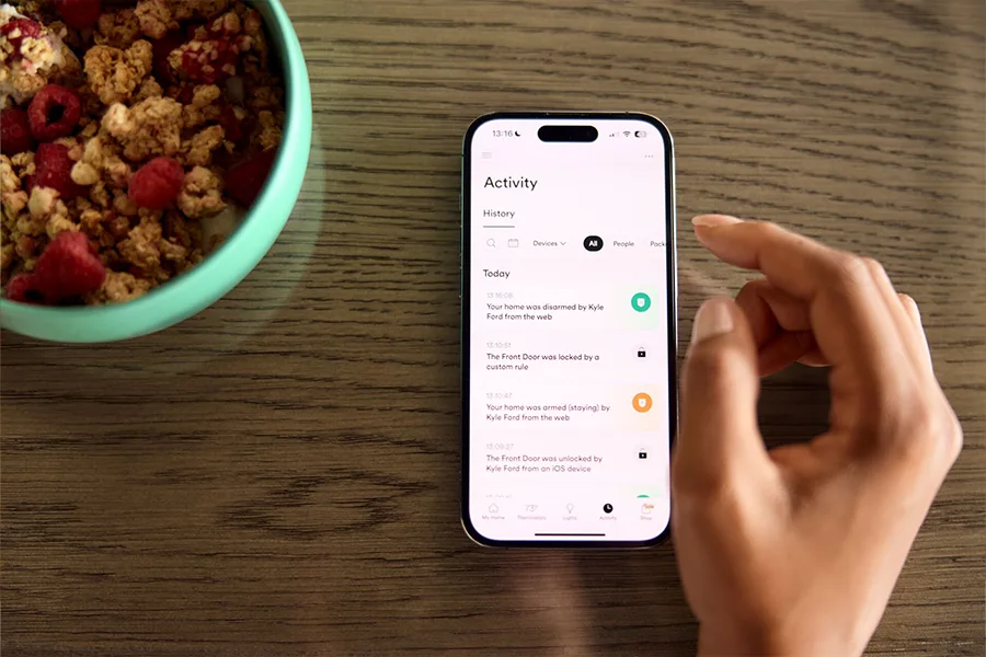 Homeowners are alerted through the Vivint App whenever a safety device triggers. Person using the Vivint App on a breakfast table